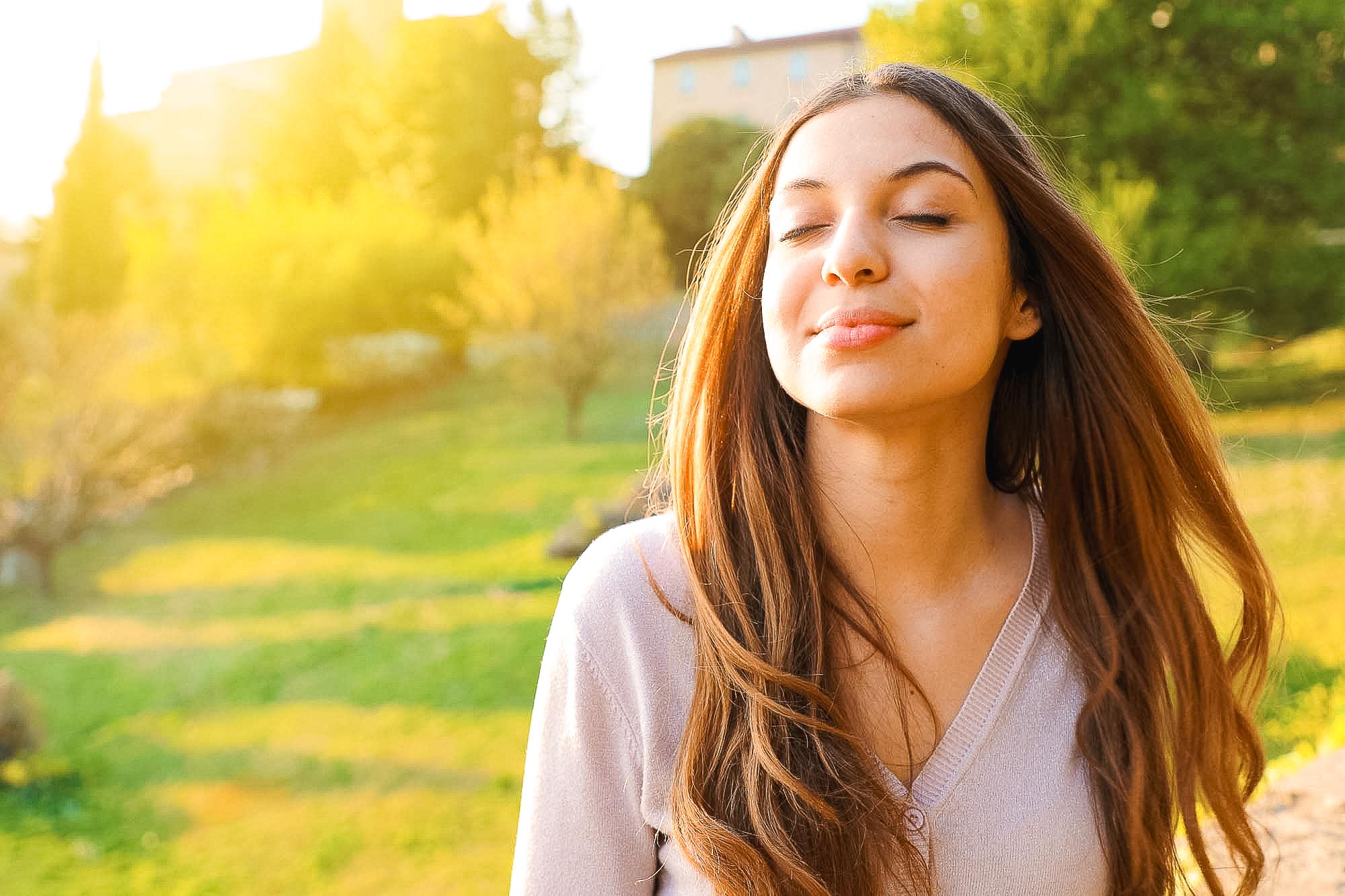 Woman smiling looking up taking deep breath celebrating freedom. Group of young adults talking outside